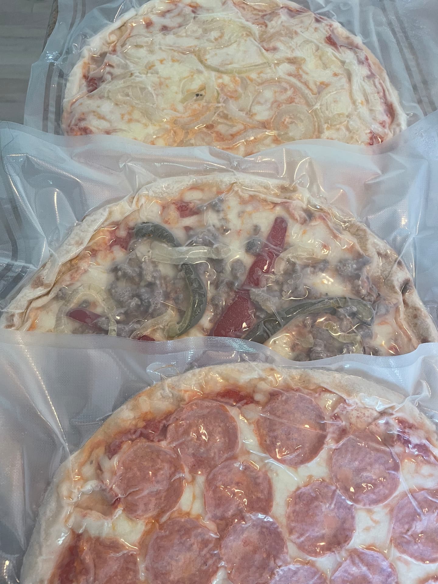Vacuum-sealed frozen pizza packages